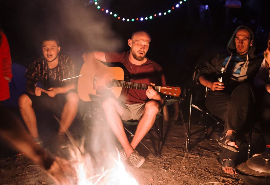 The lads sitting around a campfire singing - a boys weekend near Perth to remember as a Bachelor party idea